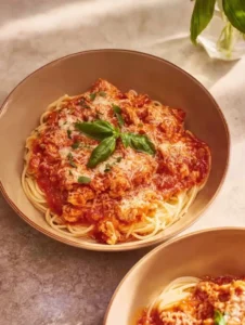 Ground Chicken Parmesan topped with cheese and herbs, served with pasta.